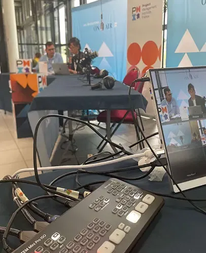 Régie technique du plateau radio pendant un direct : mélangeur, câbles et retour vidéo.